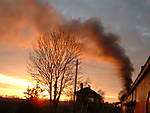 The setting sun catches the exhaust of an engine in Cranmore Station, ESR